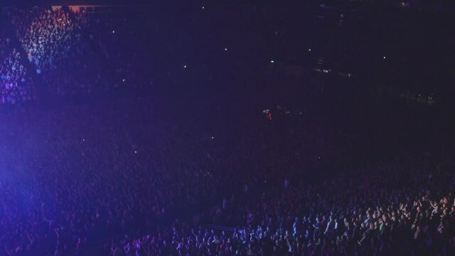 Huge crowd of people in stands at an arena concert, extreme wide panoramic view