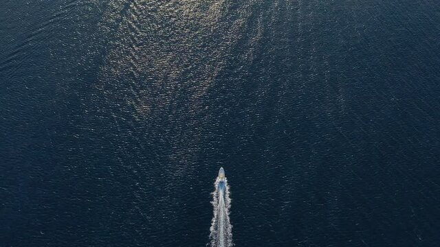 Speedboat travelling through ocean, wake behind motorboat, aerial top down view