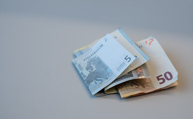 Cash or Euro paper money notes on light gray background. Folded pocket money earnings. Copy space.