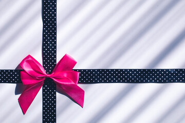 Pink bow on dotted black ribbon. Gift, celebration background concept