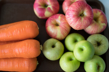 Red and green apples with carrots on plate for cold press juicer.Healthy food concept.Different color.