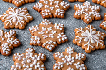 Obraz na płótnie Canvas Christmas homemade gingerbread cookies in the shape of snowflakes and herringbone on a blue background. Holiday sweets for decoration and gifts.