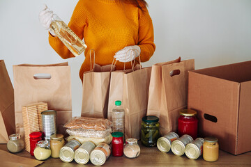 woman in medical gloves packing food for donation