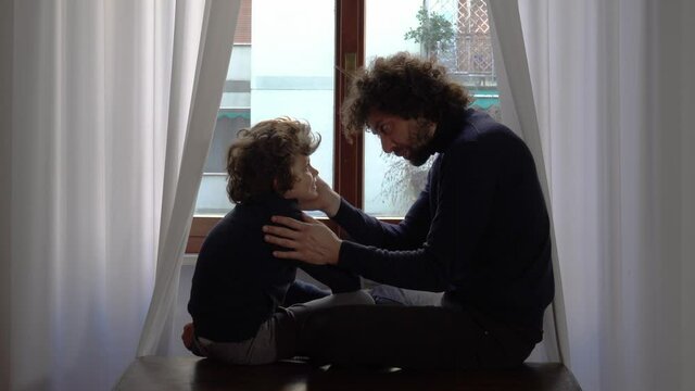 Europe, Italy , Milan -  Father and children boy  six years  at home during quarantine  due covid-19 Coronavirus outbreak - lifestyle in apartment - look and say hello from the window 