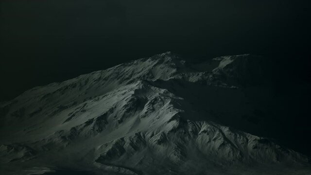 Dramatic dark rocky mountain with patches of snow in storm