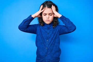 Cute hispanic child with long hair wearing casual clothes suffering from headache desperate and stressed because pain and migraine. hands on head.