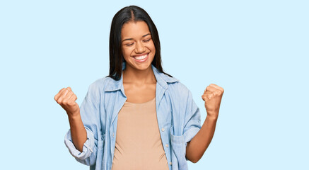 Fototapeta na wymiar Beautiful hispanic woman expecting a baby showing pregnant belly very happy and excited doing winner gesture with arms raised, smiling and screaming for success. celebration concept.