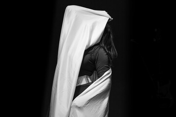 Black and white photography of a female dancer performing with a white cloth in a black background.
