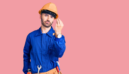 Young hispanic man wearing worker uniform doing italian gesture with hand and fingers confident expression