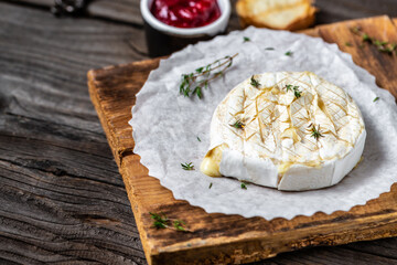 Traditional French homemade baked Camembert cheese with thyme and baguette bread on wooden table