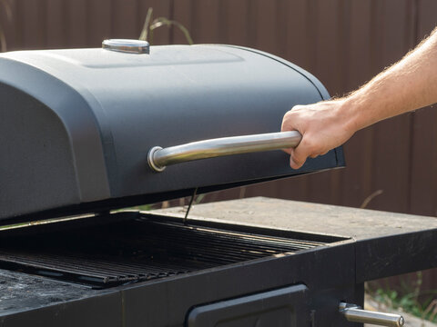 Male Hand Opened The Lid Of The Barbecue Grill