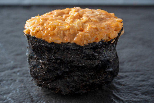 spicy guncan with chicken and spicy sauce on a dark textured surface. Side view