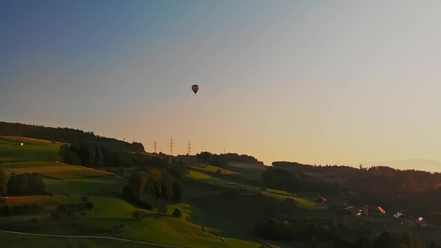 hot air balloon flying over some beautiful hills in switzerland, the sun is setting