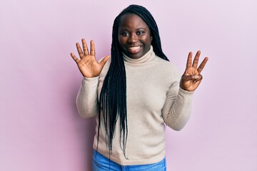 Young black woman with braids wearing casual winter sweater showing and pointing up with fingers number eight while smiling confident and happy.