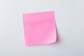 Pink sticky note on white wall. Making notes