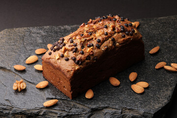 Homemade banana bread with walnut, almonds on a stone background.