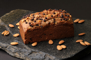 Homemade banana bread with walnut, almonds on a stone background.