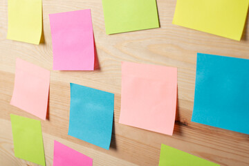 Sticky papers on wooden table placed randomly. Concept of brainstorming