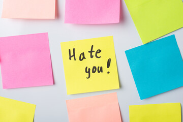 Hate you description on a yellow note paper on a board. Concept of dislike