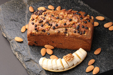 Homemade banana bread with walnut, almonds on a stone background.