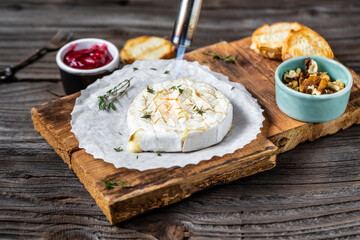 Delicious hot baked camembert with fresh thyme, cranberry sauce and baguette bread on wooden table. banner, catering menu recipe place for text, top view