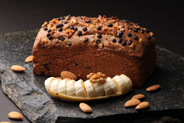 Homemade banana bread with walnut, almonds on a stone background.
