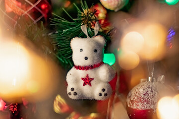 Interesting Christmas toys on the Christmas tree. Christmas accessories in white, among flashing lanterns and lights. Festive and elegant cute things for family holidays.