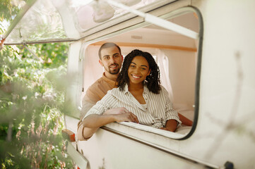 Couple looks out of rv window, camping in trailer