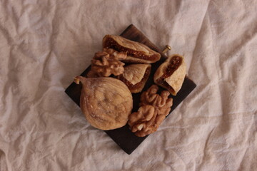Dried food and nuts for diet food and healthy lifestyle. Top view walnuts and dried fig on the brown plate, closeup. Space for text.