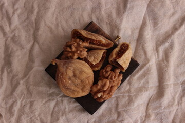 walnuts and dried figs and dried fig slices on the brown wooden plate for healthy life, top view. Space for text.