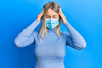 Beautiful blonde woman wearing covid-19 medical mask suffering from headache desperate and stressed because pain and migraine. hands on head.