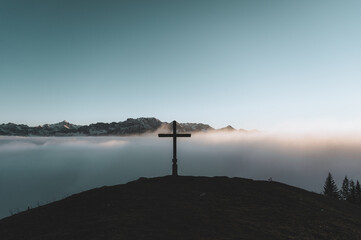 Gipfelkreuz im Allgäu bei Nebel und Sonnenuntergang
