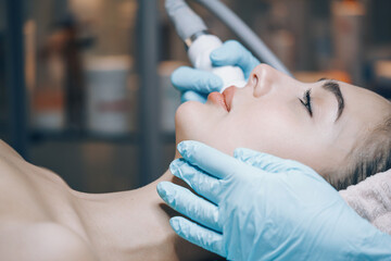 doctor performs cosmetic procedures in a beauty salon on the face of a young woman