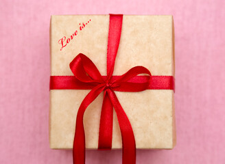 Gift box with a red bow on a pink background. Gift for lovers