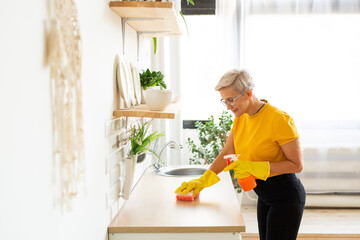beautiful adult woman with glasses in a yellow t-shirt does house cleaning