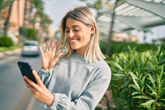 Young blonde girl smiling happy doing video call using smartphone at the city