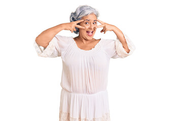 Senior woman with gray hair wearing bohemian style doing peace symbol with fingers over face, smiling cheerful showing victory