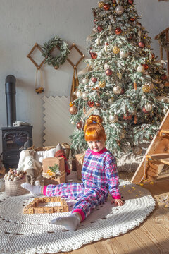 happy little girl playing near christmas tree at home, winter holidays, real people
