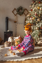 happy little girl playing near christmas tree at home, winter holidays, real people