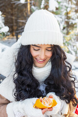 beautiful young woman holding in arms tangerine in winter fairy forest