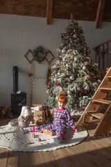 happy little girl playing near christmas tree at home, winter holidays, real people