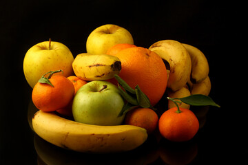 Fruits tangerines, apples and bananas on a black background