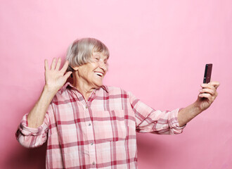 old grandmother is talking to her grandchildren by phone, smiling and greeting them.