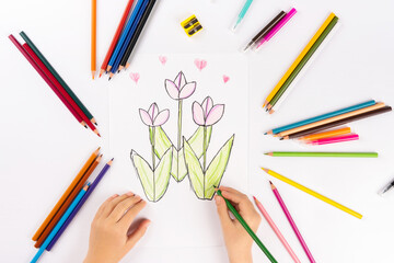 Child girl flowers with multicolored felt-tip pens on a white sheet.