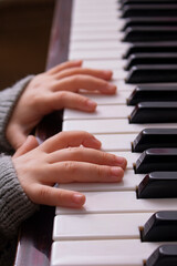 Fototapeta premium Cropped hands of girl playing piano at home