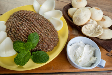 raw quibe with sliced onion, dried curd, pita bread and mint leaves