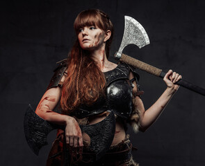 Mighty northern woman warrior in light armour with brown hairs poses in dark background with two...