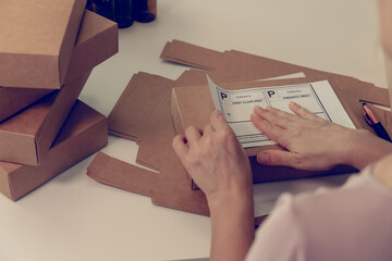 Close-up of woman hands at table with cardboard boxes