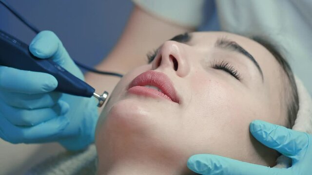 doctor performs cosmetic procedures in a beauty salon on the face of a young woman