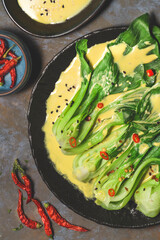 Pak Choi or  Bok Choy,  or Chinese Kale prepared  in fusion-style with curry sauce, chilli and kaney pepper  on the textured background, close-up